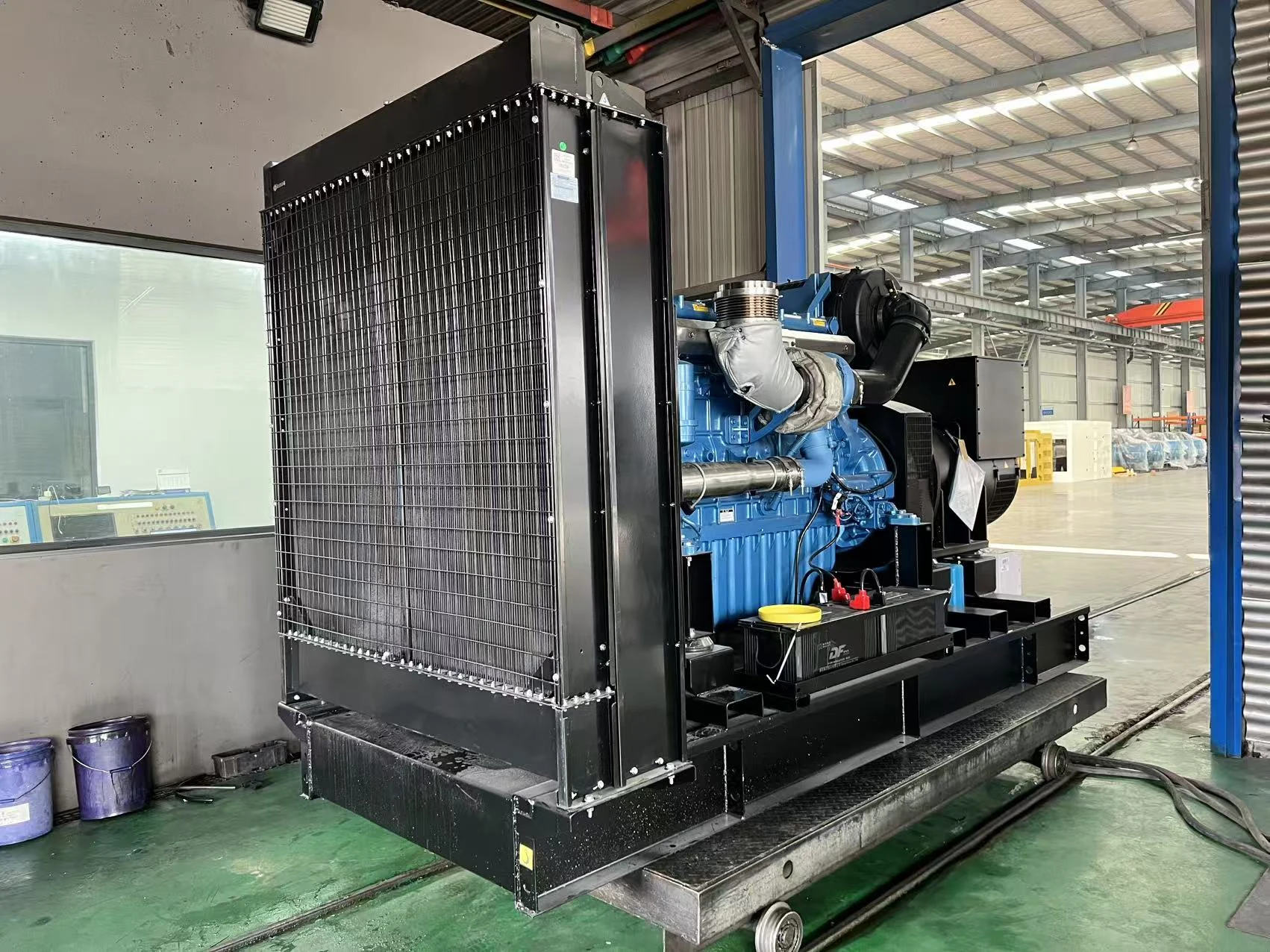 Generator radiator and engine on a wheeled platform beside the factory test bay